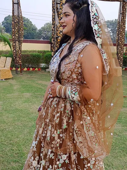 A side profile of a client in a brown floral embroidered lehenga, her hair styled in beautiful waves.