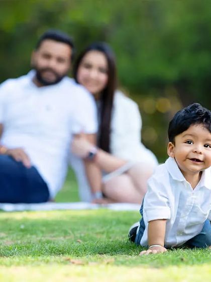 A toddler crawls towards the camera with his parents smiling in the background. This composition creates a lovely sense of depth and focuses on the child's milestone.