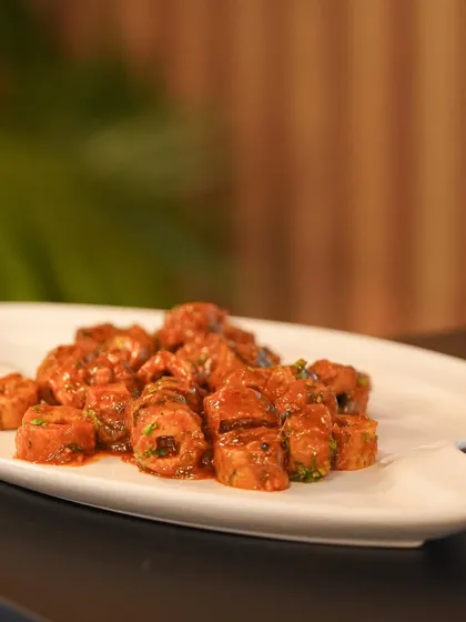 Bite-sized seekh kebabs tossed in a savory sauce, perfect for serving at events where guests are mingling.