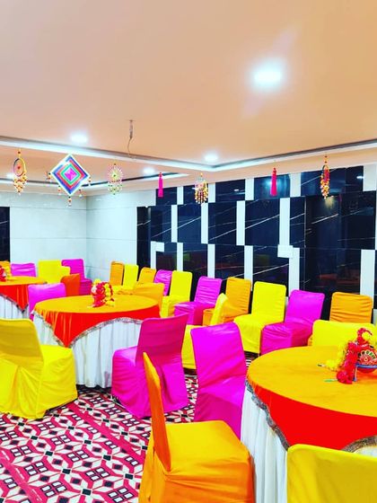 The colourful seating and tables arranged neatly in the hall, with traditional hangings suspended from the ceiling.