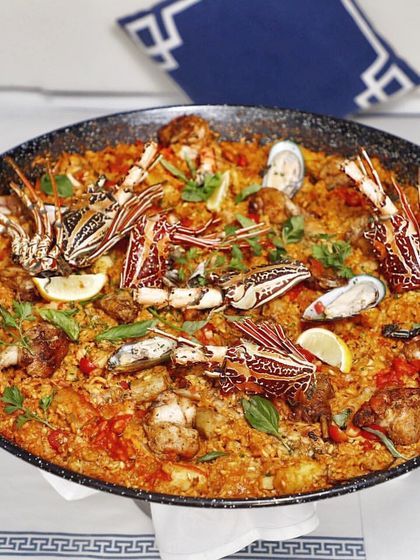 A magnificent Paella Valenciana, generously filled with lobster, chicken, and fresh seafood. This is a dish for celebration, meant to be placed in the center of the table for everyone to enjoy.