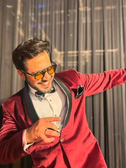 Striking a dance pose in a stylish red tuxedo. I believe the host's energy and style sets the tone for the entire event.