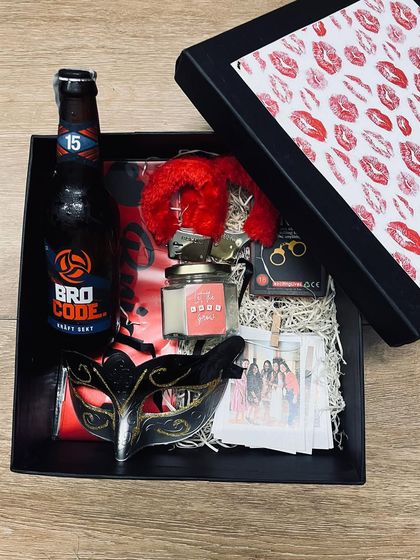 A kinky "Kiss the Miss Goodbye" hamper for the bride-to-be. This fun bachelorette gift includes a "Bro Code" beer, a masquerade mask, naughty handcuffs, and polaroids of her bride tribe.