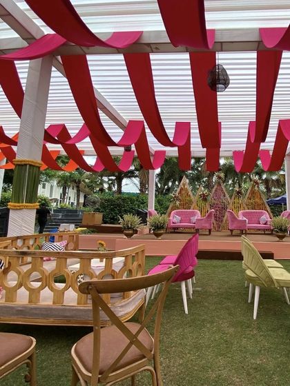 Another angle of the colorful Mehandi decor, showing the different seating arrangements we provide. We mixed traditional wooden benches with modern pink and green chairs to create varied and interesting lounge areas for guests.