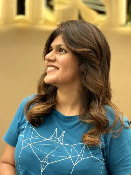 A happy client showing off her new hair color, which adds warmth and dimension. The soft curls complement the look perfectly.