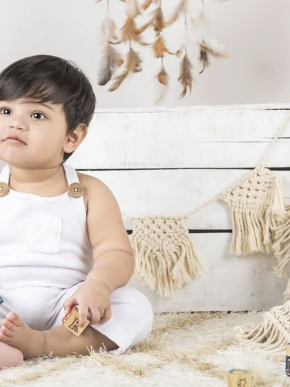 A curious little boy playing with alphabet blocks in a simple, bright studio setting.