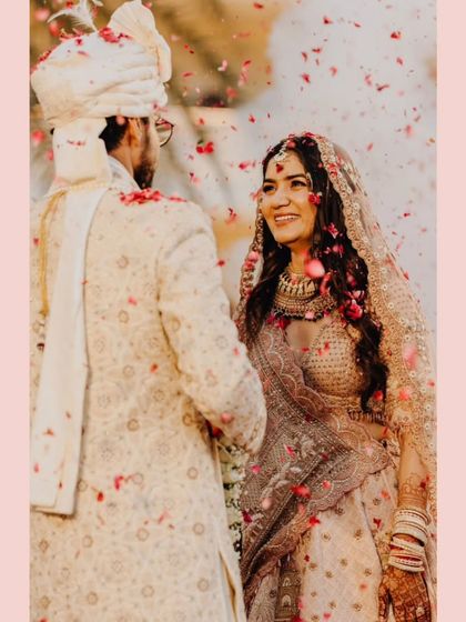 A classic Varmala moment, with the bride's beautiful smile as she looks at her groom, framed by a shower of rose petals.