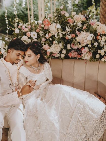 An intimate portrait of the couple on a couch surrounded by flowers at their engagement.