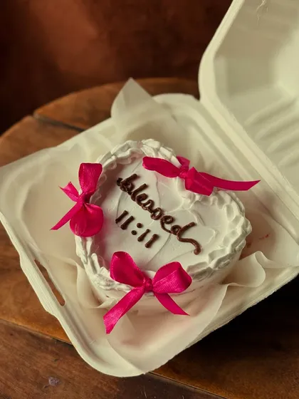 A different angle of the heart-shaped "blessed 11:11" bento cake, showing it nestled in its eco-friendly packaging.
