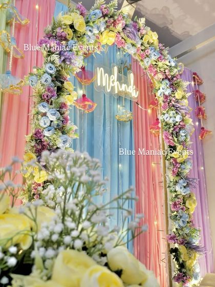 A detail shot of the pastel Mehendi arch, seen from a low angle. It showcases the delicate baby's breath flowers mixed in with the larger pastel blooms.