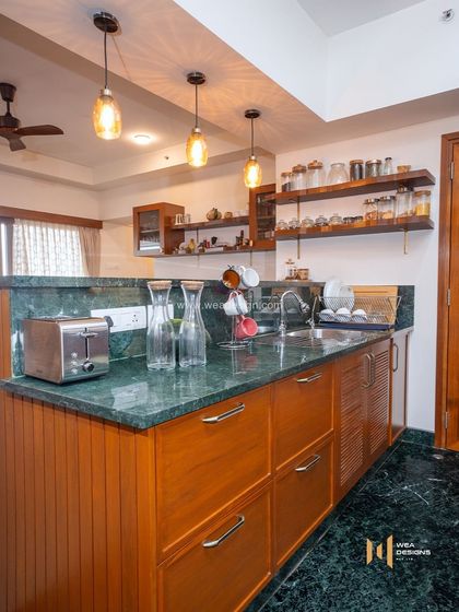 The kitchen in the Total Environment project, with green marble countertops, veneer cabinets, and open shelving for a rustic yet refined look.