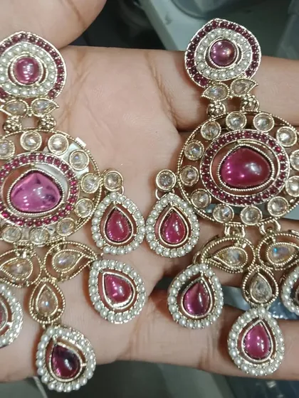 A pair of chandbali-style earrings with beautiful pink stones and pearl borders.
