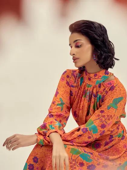 A close-up on a beautiful orange floral print dress with a high neck, showcasing the intricate details and vibrant colors of the garment.