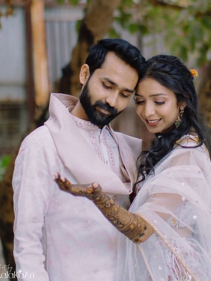 A sweet portrait showing the bride admiring her henna-adorned hand with her groom. A beautiful way to capture this pre-wedding detail.