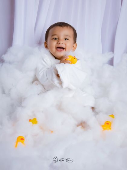 Playing with rubber ducks in a sea of clouds, this little one is all smiles during his fun and imaginative milestone shoot.
