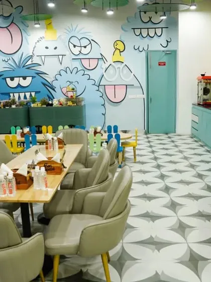 A wide view of our dining area, showcasing the fun wall art and the separation between the adult seating and the colorful kids' tables.