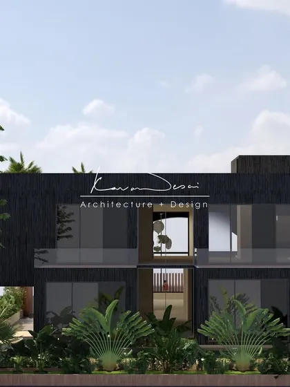 A modern, two-story home designed with a bold, dark facade. The large glass windows and open balconies prevent the structure from feeling heavy, while the surrounding tropical plants ground it in its environment.