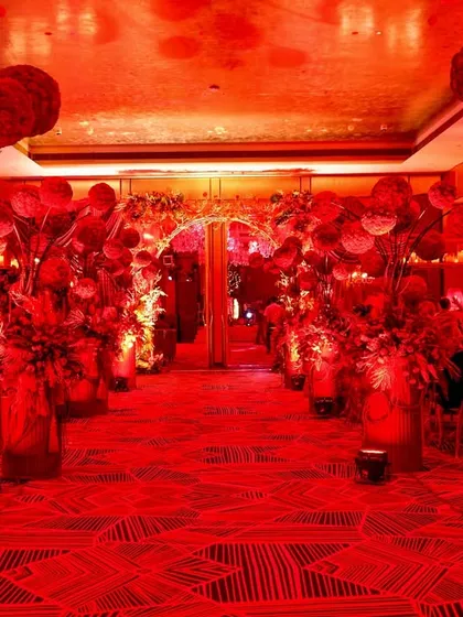 The grand entrance to the red-themed birthday party. The entire hallway was bathed in red light and lined with dramatic floral arrangements to create a powerful first impression.