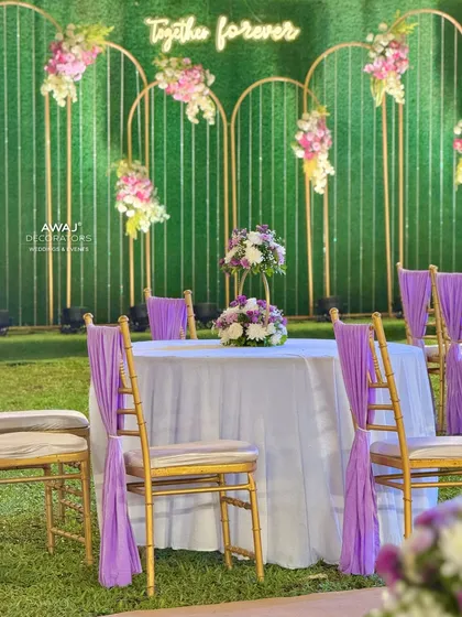 A guest table with a simple yet elegant floral centerpiece, set against the backdrop of the "Together Forever" photo wall.