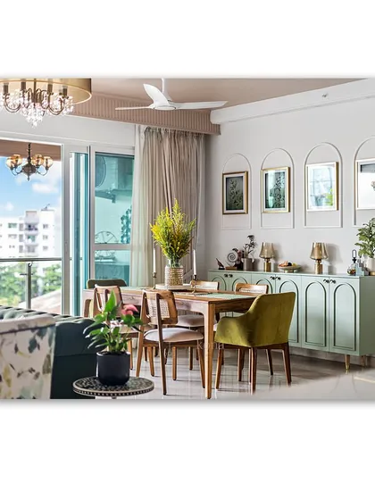 A beautiful dining area with a mint green sideboard and arched wall frames. The mix of a wooden table, olive green chair, and elegant chandelier creates a fresh, stylish, and inviting space for dining.