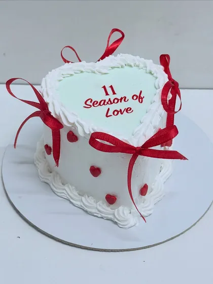 A sweet heart-shaped cake perfect for Valentine's Day or an anniversary. This chocolate truffle cake is decorated with red ribbons and hearts, celebrating a season of love.