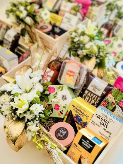 A gift given with love is the most precious thing. These gourmet hampers are overflowing with delicious snacks, coffee, and treats, all beautifully arranged with fresh white flowers in a pinewood tray.