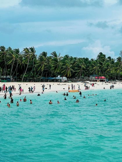 People enjoying the crystal-clear turquoise waters of a Lakshadweep beach, a perfect depiction of a tropical vacation.