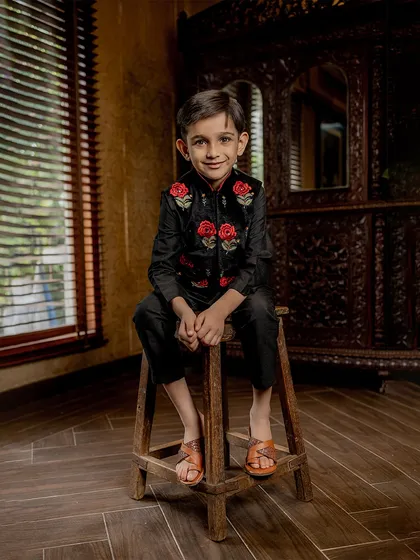 A seated portrait of our young model in the black and red rose Bundi set. He looks comfortable and confident, ready to steal the show.