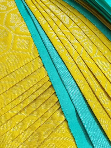 A pre-pleated client saree in a vibrant yellow and turquoise combination, neatly folded and ready for delivery.