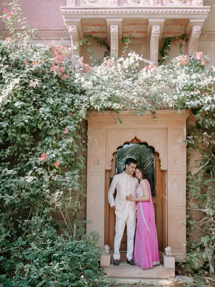 A fairytale moment for Saloni and Kanav, framed by a traditional Rajasthani doorway and beautiful bougainvillea. This shot blends natural beauty with stunning heritage architecture.