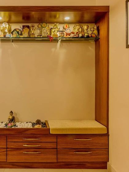 A functional foyer designed to be a pause point before entering the main home. This custom wooden unit combines a shoe cabinet, a comfortable seating bench, and an illuminated shelf for displaying personal treasures.