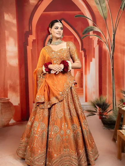 A beautiful orange lehenga with intricate gold embroidery, a warm and vibrant choice for a wedding celebration.