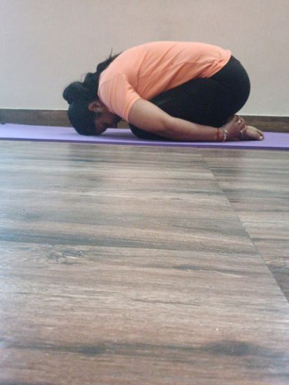 A student rests in Balasana (Child's Pose). This gentle posture is excellent for releasing tension in the back, shoulders, and chest, and it has a profoundly calming effect on the mind.