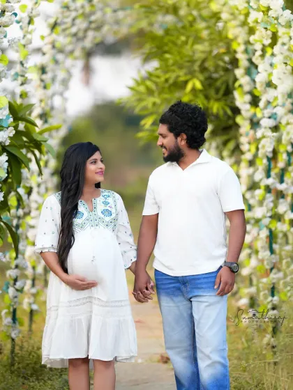 A joyful outdoor couple portrait. Walking hand-in-hand under a floral arch, their smiles and the natural light create a bright and happy memory.