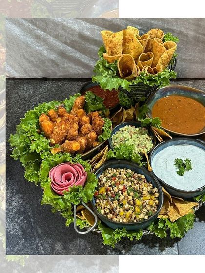 A Mexican platter with a creative touch. We've arranged the nachos, dips, and other bites in an artistic way, even carving a rose from a beetroot to add a touch of elegance.