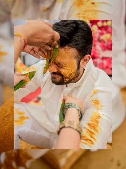 A close-up of the groom wincing playfully as turmeric paste is applied to his face during the Haldi ritual.