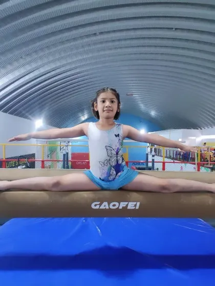 Perfect form on the balance beam. This student demonstrates a flawless split, showcasing the results of our dedicated training programs.