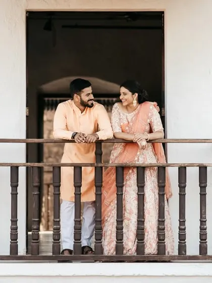 Nikhil and Varsha sharing a quiet moment on a balcony in a Goan villa, dressed in elegant traditional wear.