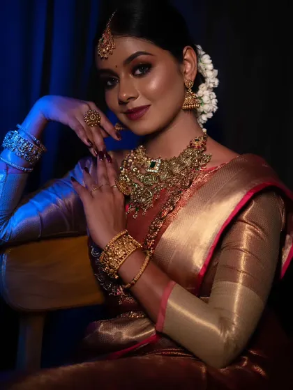 A dramatic shot of a model in a traditional look. The lighting highlights the contours of her face and the richness of the makeup.