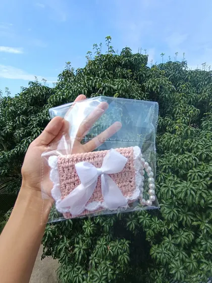 A pink and white pocket purse with a pearl strap, shown in its clear packaging. This is a great grab-and-go item for retail.