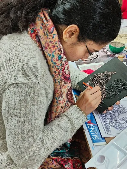 A student carefully working on a detailed relief piece of a peacock. This art form requires patience and a steady hand, skills we help you develop.