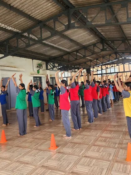 Students practice a standing yoga pose, reaching for the sky. This group activity promotes unity and shared focus, enhancing the calming effects of the practice.