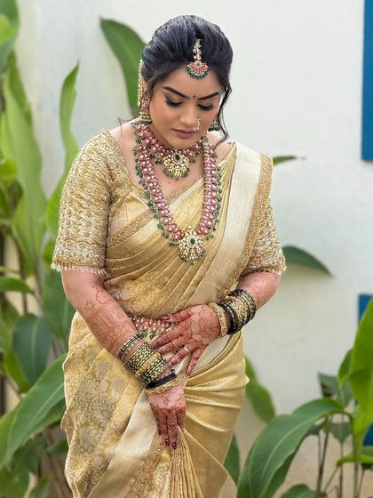A beautiful portrait of a bride in a golden Kanjeevaram saree. The makeup features a classic winged liner and a soft lip, perfect for a traditional ceremony.