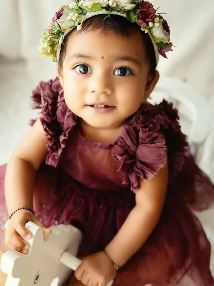A sweet portrait on a rocking horse. Using classic toys as props adds a timeless and playful element to first birthday photoshoots.