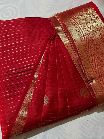 A classic red silk saree with a gold border, perfectly folded.