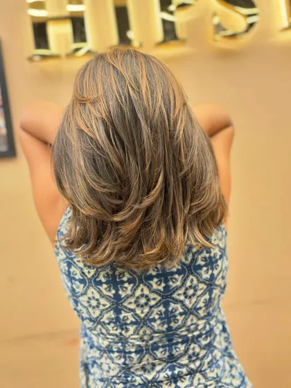 The back of a client's hair, showing off a layered cut with beautiful, natural-looking highlights.
