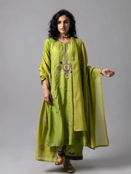 This lime green kurta set has a relaxed, flowing silhouette. The delicate floral embroidery around the neckline adds a touch of artisanal charm.