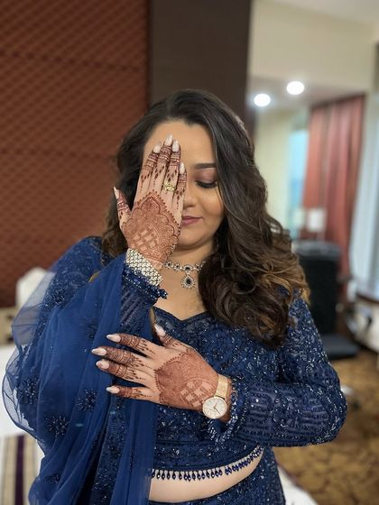 A playful pose showing off the mehndi and the beautiful manicure. The makeup is glamorous with a focus on the eyes.