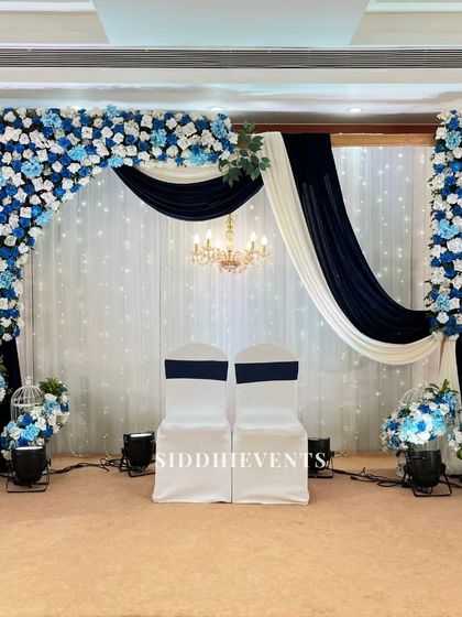 A serene and elegant stage in shades of blue and white. The floral arch and draped curtains create a sophisticated and calming atmosphere for a reception.