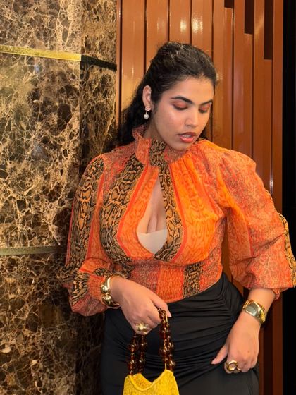 Feeling like a thrift queen in this outfit. The orange printed top, bag, and accessories are all thrifted, showing how I mix high and low fashion to create a unique, maximalist look.